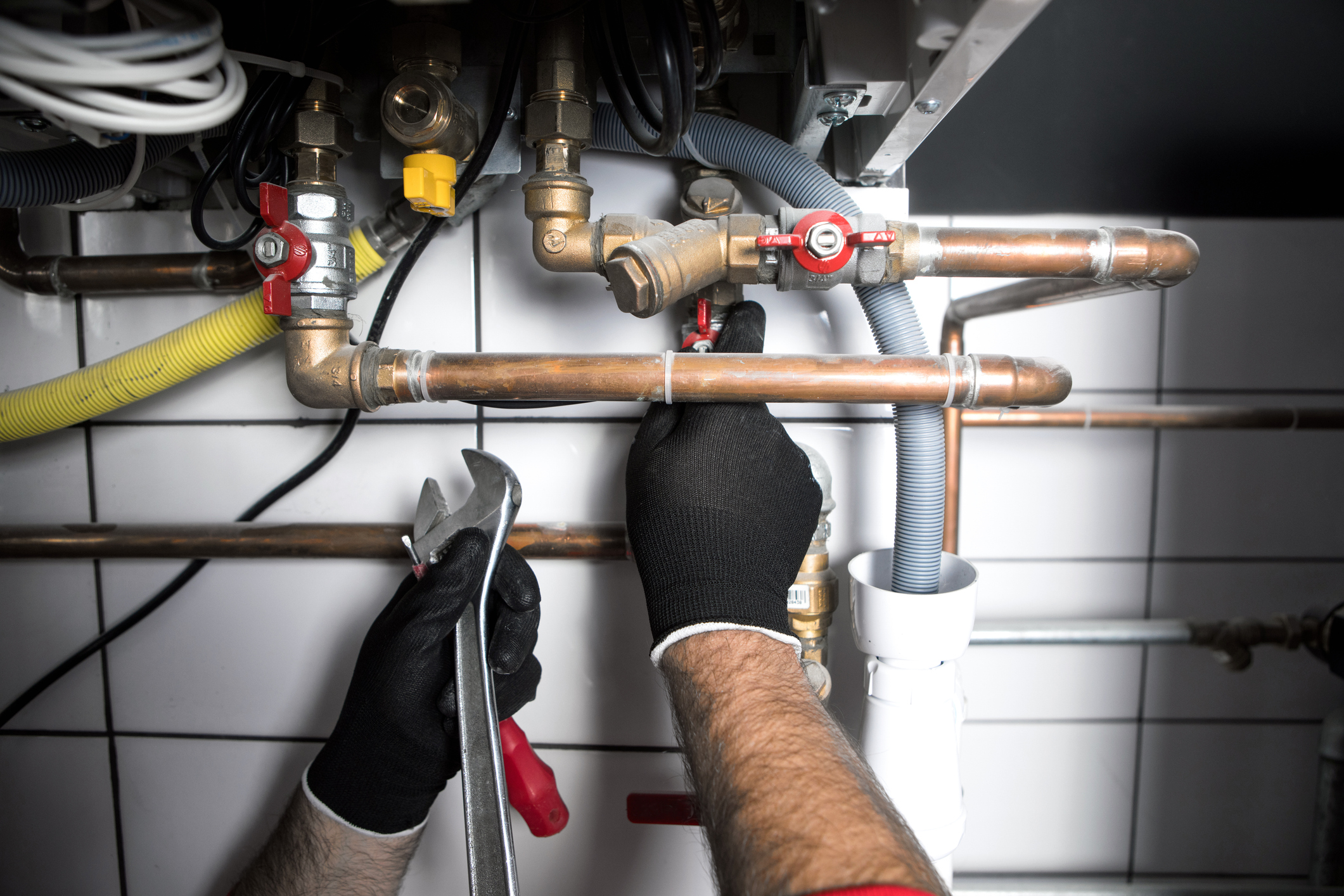 Plumber performing home repairs with plumbing materials.