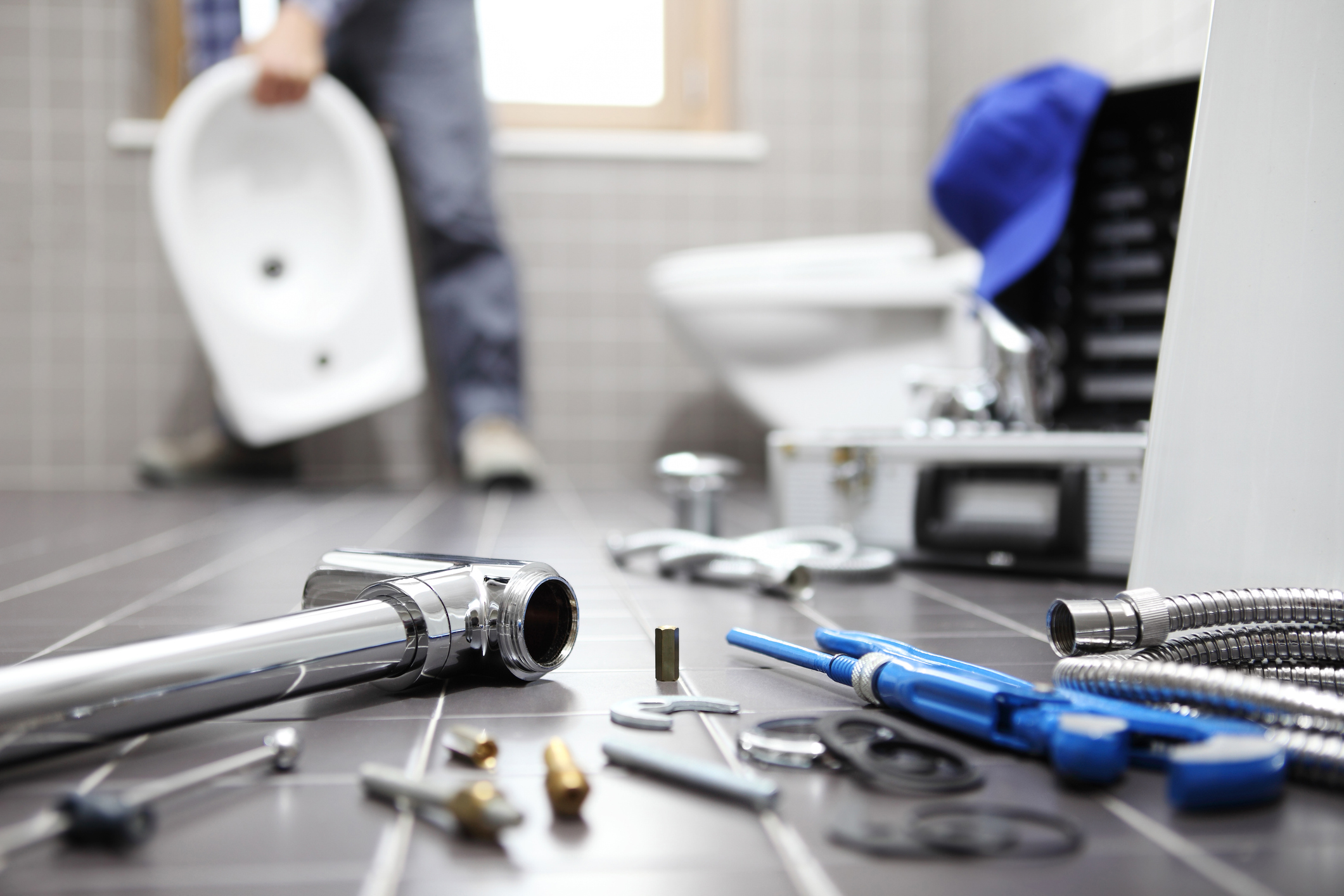 Plumber performing repairs on residential plumbing systems, Bathroom.