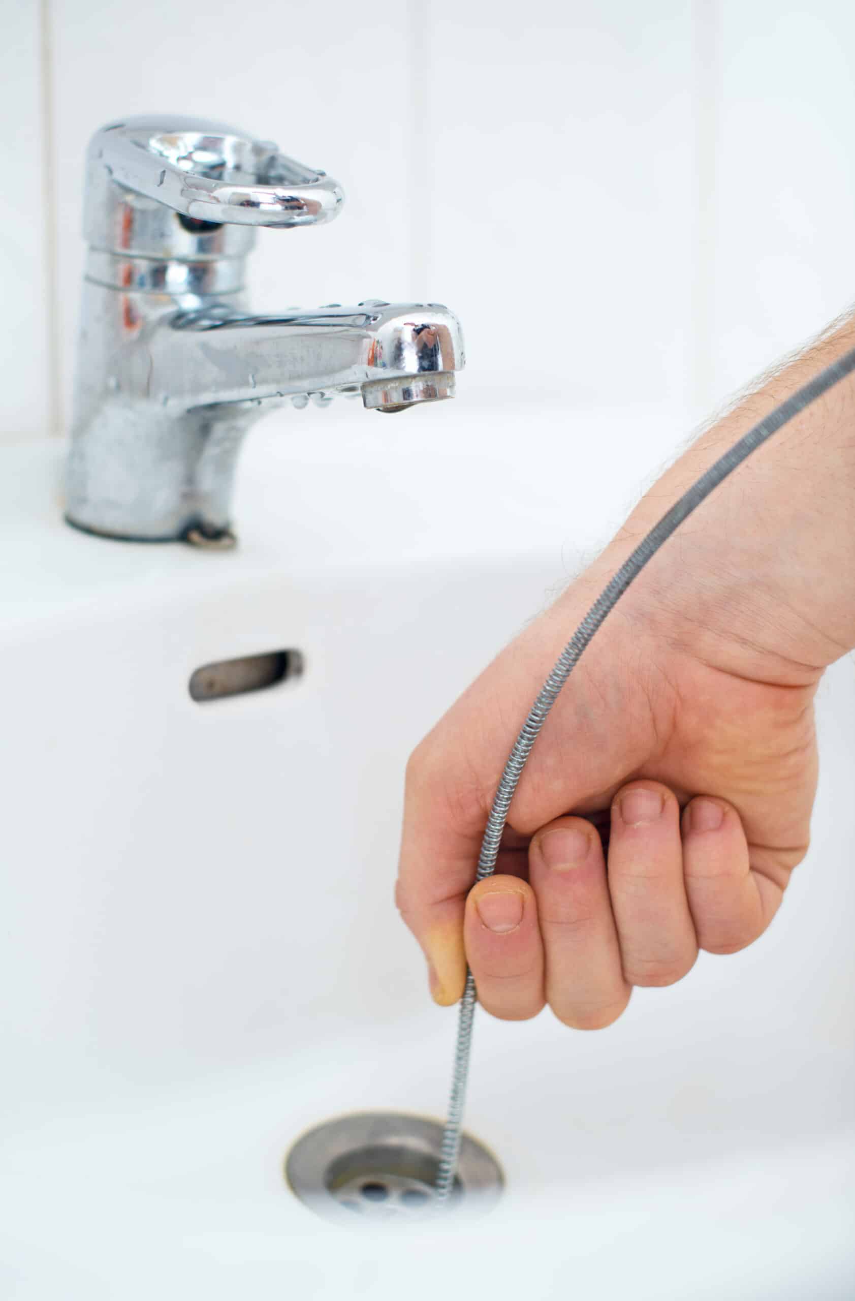 Plumber repairing sink with plumber's snake, Drain snaking.