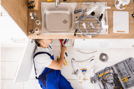 plumber fixing pipes under a sink